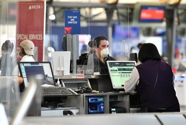 Travelers check in through plexiglass dividers at Delta at Hartsfield-Jackson. (Hyosub Shin / Hyosub.Shin@ajc.com)