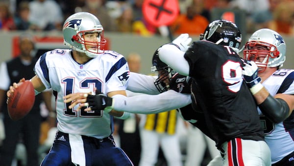 New England Patriots quarterback Tom Brady (12) looks for a receiver under pressure from Atlanta Falcons Henri Crockett (94) and Brady Smith (91) with help from teammate Joe Andruzzi (63) Sunday, Nov. 4, 2001, in Atlanta.