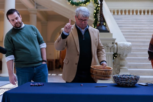 Gabriel Sterling (center) from the office of the secretary of state rolls a die in the state Capitol on Nov. 16, 2022. The dice roll was a step to randomize which ballots to review across the state in an election audit.