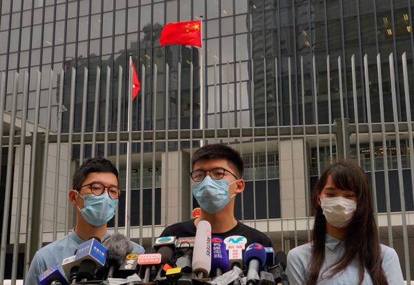 Hong Kong activist Joshua Wong, center, with Agnes Chow and Nathan Law, left,  speaks to media outside the Legislative Council Complex.