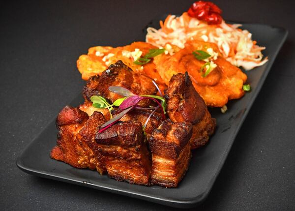 Griot (braised pork shoulder) plated with tostones (fried plantains) and pikliz (a vinegar-based slaw) at Rock Steady. STYLING BY CHRISTIAN LUCKE BELL / CONTRIBUTED BY CHRIS HUNT PHOTOGRAPHY