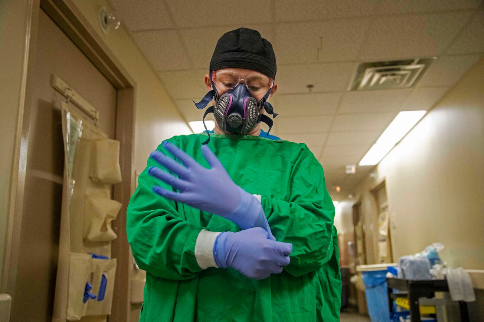 12/03/2020 —  Carrollton, Georgia —  Tanner Health System Hospital nurse Arielle [last name withheld] puts on gloves to complete her PPE ensemble as she prepares to enter a COVID-19 patients room on the Covid-19 isolation floor at Tanner Health System Hospital in Carrollton Thursday, December 3, 2020.  (Alyssa Pointer / Alyssa.Pointer@ajc.com)