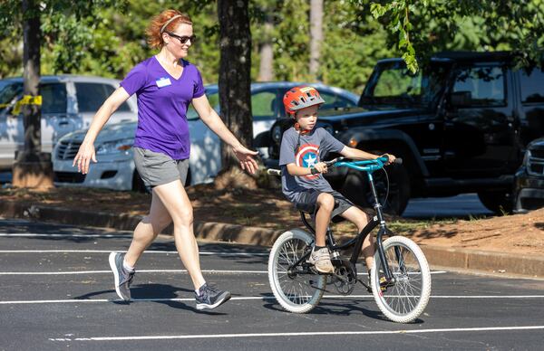 Volunteer Leslie Howard helps special-needs camper, Matthew, learned how to ride a two-wheel bike without adaptations during the iCan Bike Alpharetta camp at The Cooler in Alpharetta. PHIL SKINNER FOR THE ATLANTA JOURNAL-CONSTITUTION.