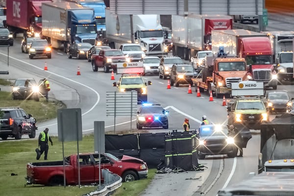 A truck involved in the crash came to a rest on the exit ramp’s grassy shoulder, where police placed a black screen to obstruct commuters’ view of the scene.