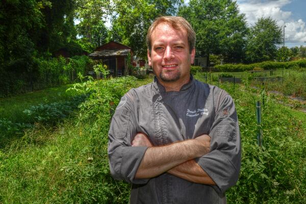 Executive chef and managing partner Derek Dollar poses in the Milton's Acre fruit and veggie garden just behind Milton’s Cuisine & Cocktails in Milton. "The garden helps food costs," he said, "and you also know where your food comes from.” (Chris Hunt for the AJC) 