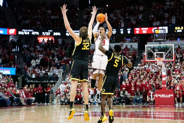 Wisconsin guard John Tonje (9) attempts a 3-point basket over Oregon center Nate Bittle (32) and guard TJ Bamba (5) during overtime of an NCAA college basketball game Saturday, Feb. 22, 2025, in Madison, Wis. (AP Photo/Kayla Wolf)