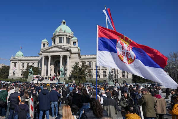 People stand in silence to commemorate the 15 victims killed after a railway concrete canopy fell in November 2024, during a Serbia's parliament session in Belgrade, Serbia, Tuesday, March 4, 2025. (AP Photo/Darko Vojinovic)