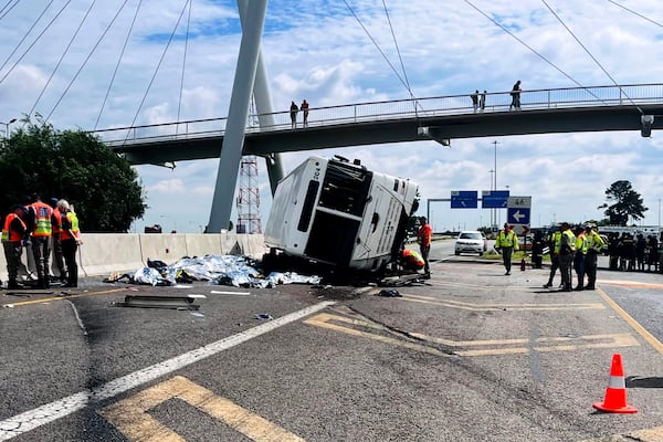 Emergency officials stand next to a bus that overturned on a highway in Johannesburg, South Africa, Tuesday, March 11, 2025, killing multiple people and injuring some. (AP Photo)