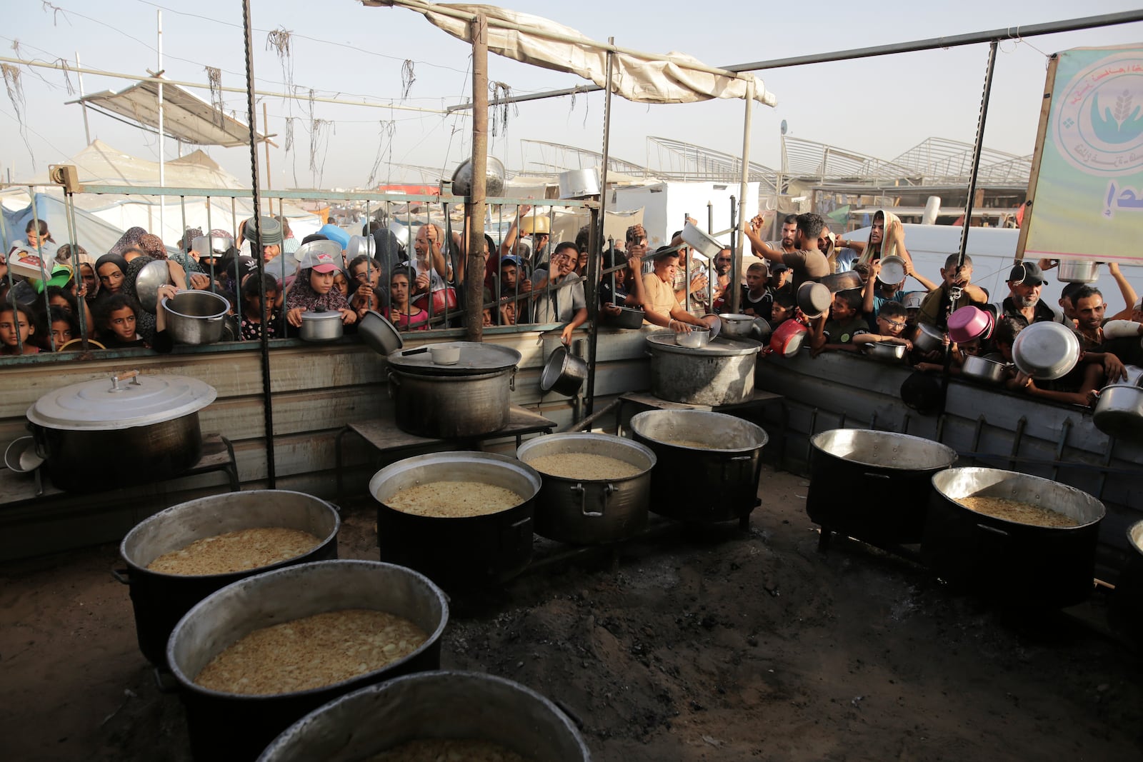 FILE - Palestinians collect food aid ahead of the upcoming Eid al-Adha holiday in Khan Younis, Gaza Strip, on June 15, 2024. (AP Photo/Jehad Alshrafi, File)