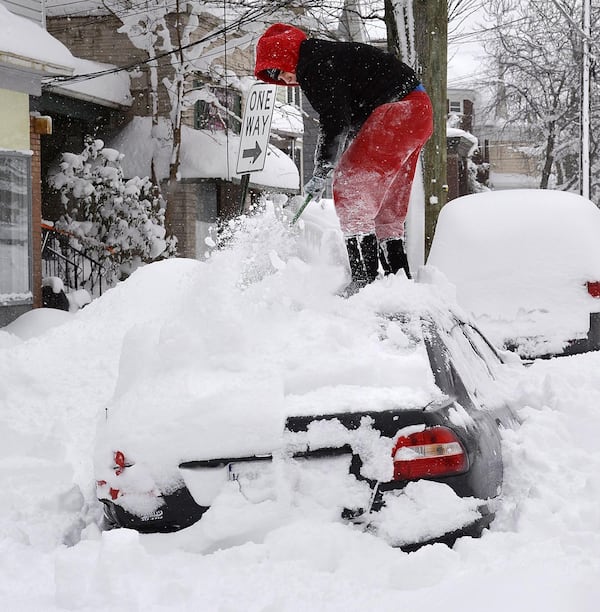 Soledda Hernandez stands on the roof of her car as she brushes off snow in Erie, Pa., Wednesday, Dec. 27, 2017. Snow continues to fall in Erie and surrounding areas that already have seen a record amount of snow over the past few days, prompting a disaster emergency declaration. 