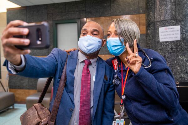 Mark Holland, left, a J&J vaccine recipient, had a question about booster shots for him, and posed for a selfie with Dr. Manning after realizing they know each other’s families. (Jenni Girtman for The Atlanta Journal-Constitution)