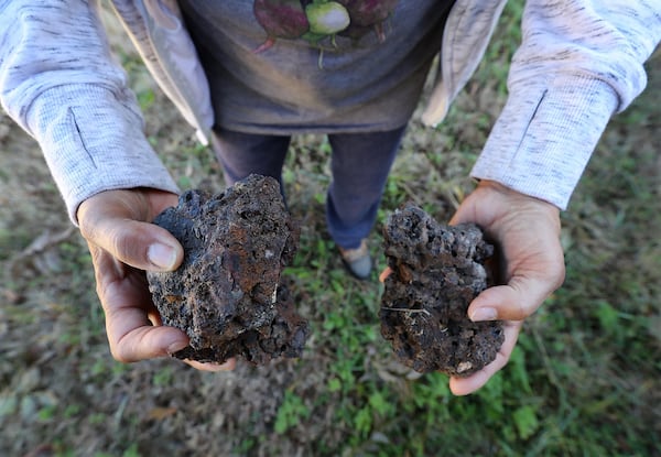 Rosario Hernandez shows off some of the chunks of slag, a byproduce of smelting, that she has found on the vacant lot next to her home near Mercedes-Benz Stadium on Monday, Nov. 25, 2019, in Atlanta. CURTIS COMPTON / CCOMPTON@AJC.COM