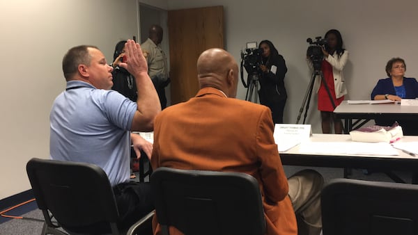 Gwinnett County Commissioner Tommy Hunter, left, takes an oath before declining to answer questions during the Gwinnett County ethics board’s Wednesday morning hearing. TYLER ESTEP / TYLER.ESTEP@AJC.COM