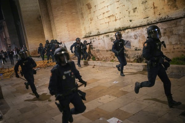 Riot police chases demonstrators during minor clashes after a peaceful protest organized by social and civic groups, denouncing the handling of recent flooding under the slogan "Mazón, Resign," aimed at the president of the regional government Carlos Mazon, in Valencia, Spain, Saturday, Nov. 9, 2024. (AP Photo/Emilio Morenatti)