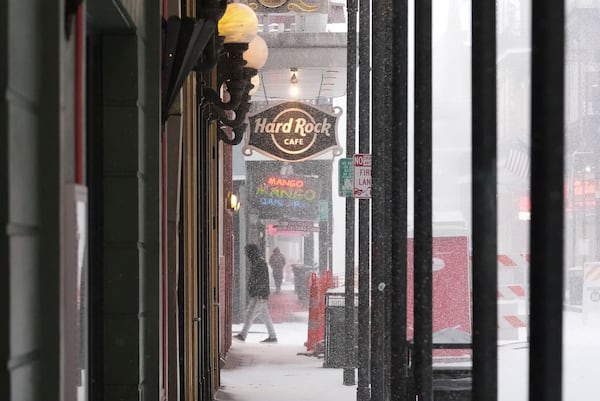 People walk on Bourbon Street during a very rare snowstorm in New Orleans, Tuesday, Jan. 21, 2025. (AP Photo/Gerald Herbert)