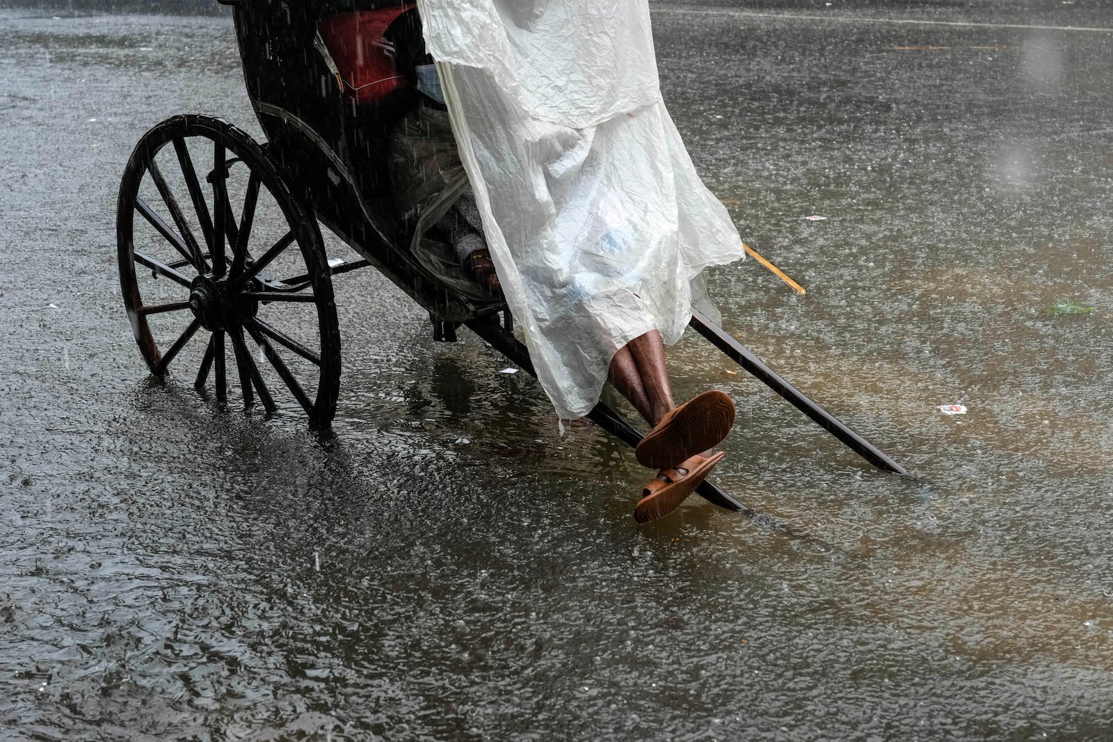 A hand-rickshaw putter waits for customers amidst a waterlogged street during heavy rain following tropical storm Dana, in Kolkata, India, Friday, Oct. 25, 2024. (AP Photo/Bikas Das)