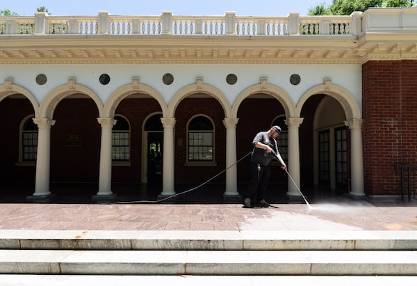 Landscape maintenance technician Josh Conley washes the exterior of the Piedmont Park Visitors' Center in Atlanta on Tuesday, June 25, 2024. (Seeger Gray / AJC)