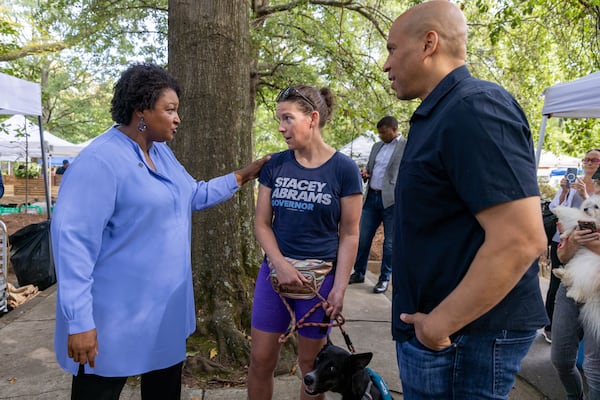 Stacey Abrams, left, and New Jersey U.S. Sen. Cory Booker talk with Kathryn Spangler during a stop earlier this month at the Freedom Farmers Market. Steve Schaefer/steve.schaefer@ajc.com)