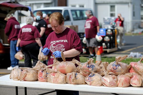 A woman helps prepare bags of food to load food during a drive-thru food distribution service April 4, in front of Highland Avenue Baptist Church in Elmwood Place, Ohio. At least 800 vehicles passed through, each receiving a pre-packed 40-pound emergency food box with staples like peanut butter, spaghetti, canned fruits, vegetables, oatmeal, and chili, and two gallons of milk, a frozen chicken, 18 eggs and produce from the Freestore Foodbank of Cincinnati, according to Jessie Fossenkemper, the community partnership manager.