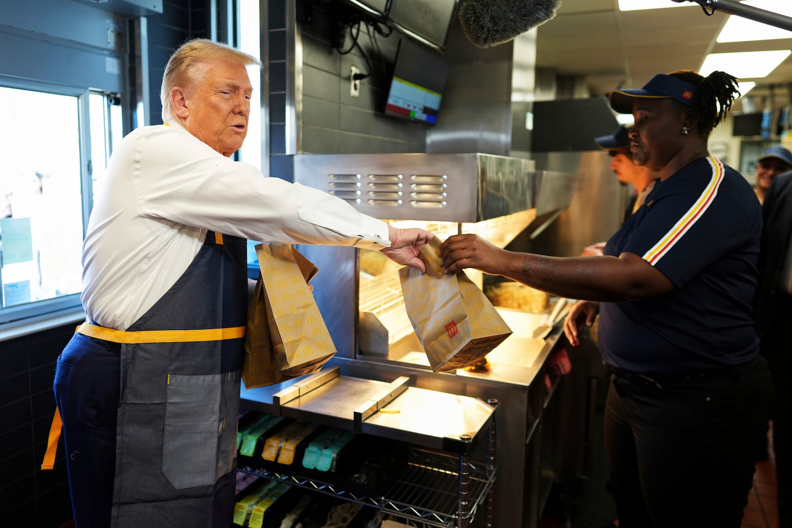 An employee hands an order to Republican presidential nominee former President Donald Trump during a visit to McDonald's in Feasterville-Trevose, Pa., Sunday, Oct. 20, 2024. (Doug Mills/The New York Times via AP, Pool)