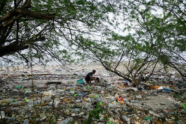 FILE - A man collects items along a polluted coastal area in Metro Manila, Philippines, Sept. 16, 2022. (AP Photo/Aaron Favila, File)