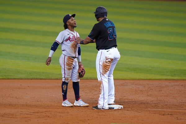 Marlins Jesus Aguilar (24) jokes with Braves second baseman Ozzie Albies during the first inning of a baseball game, Friday, June 11, 2021, in Miami. (AP Photo/Wilfredo Lee)