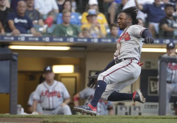 Ozzie Albies slides safely at home plate after a daring dash in the first inning of Thursday’s game at Milwaukee. (AP Photo/Morry Gash)