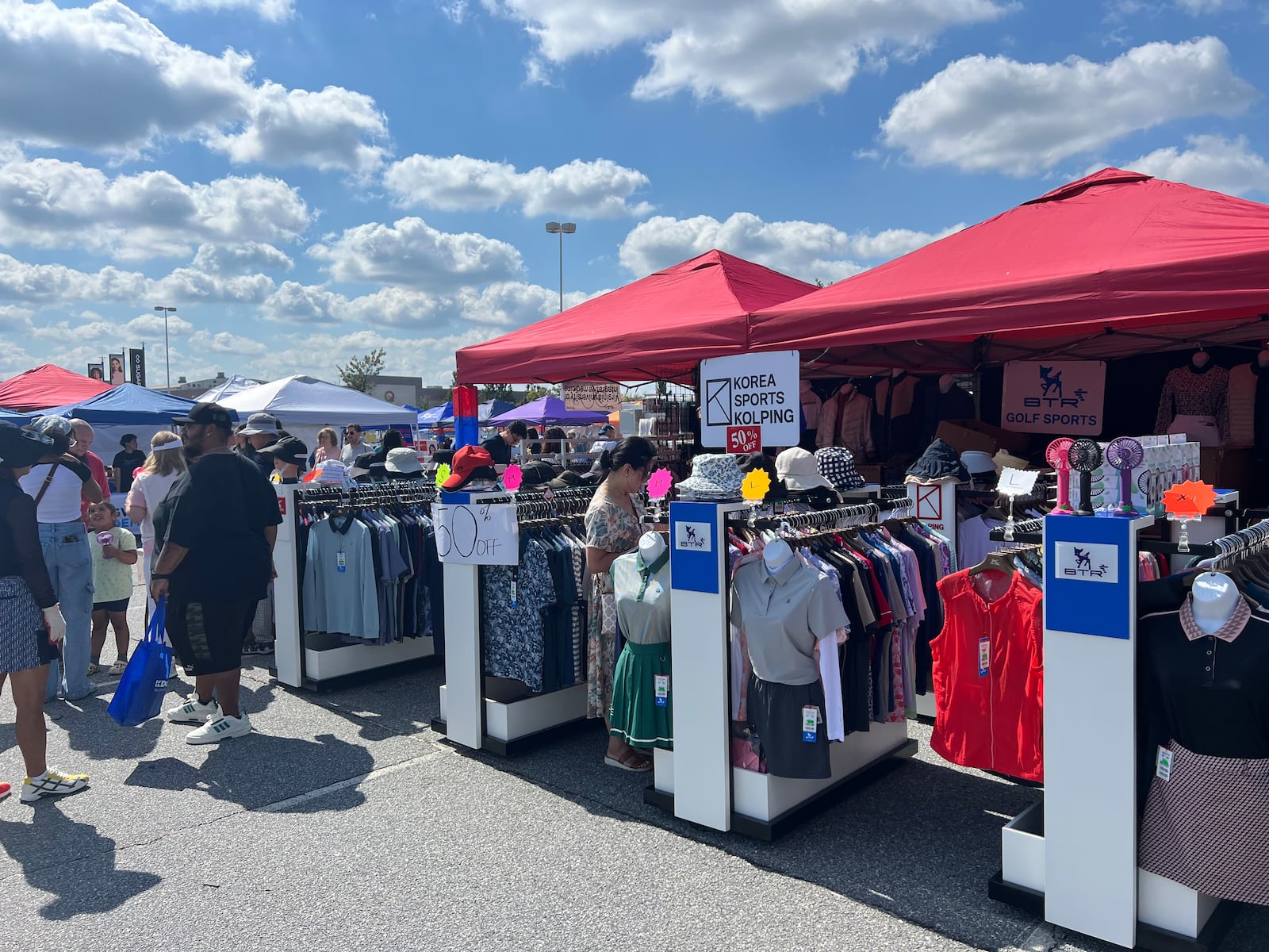 Lebih dari 100 vendor berbaris di bawah tenda di tempat parkir Sugarloaf Mills untuk Festival Korea 2024, termasuk satu vendor yang menjual pakaian golf.