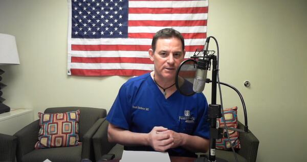 Dr. Scott Barbour, an orthopedic surgeon with clinics across metro Atlanta, is affiliated with America's Frontline Doctors, a conservative political association known for spreading conspiracy theories and unproven claims about the pandemic. On his "Doctor's Lounge" podcasts, Barbour promotes vaccine hesitancy and derides face masks. This image is from a YouTube video of a podcast recording in March 2020.