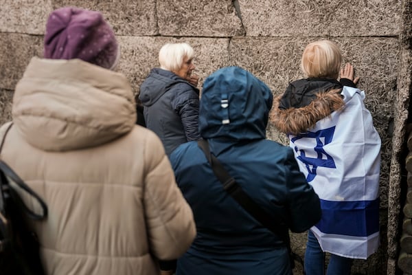 Survivors and relatives place candles near the Death Wall during a ceremony at the Auschwitz-Birkenau former Nazi German concentration and extermination camp, in Oswiecim, Poland, Monday, Jan. 27. 2025. (AP Photo/Oded Balilty)