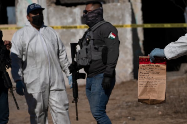 FILE - A forensic technician holds a bag of evidence collected during an excavation on a plot of land referred to as a cartel "extermination site" where burned human remains are buried, on the outskirts of Nuevo Laredo, Mexico, Feb. 8, 2022. (AP Photo/Marco Ugarte, File)