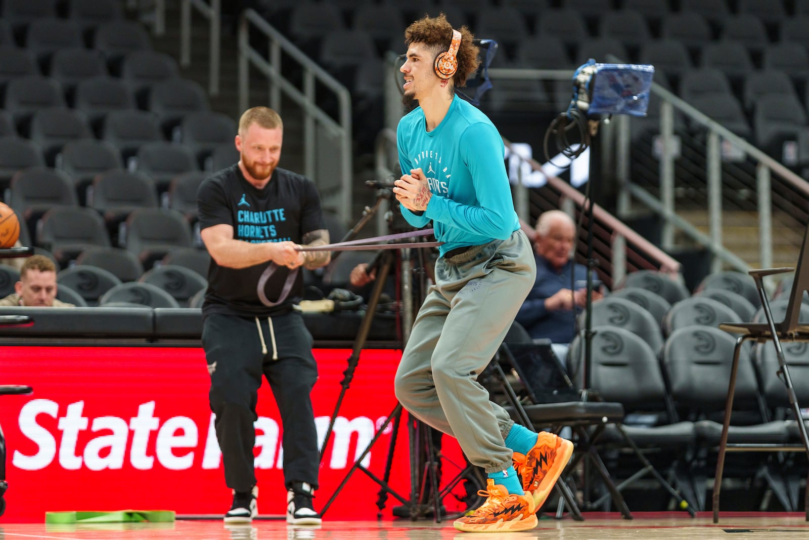 Charlotte Hornets guard LaMelo Ball (1) stretches with a trainer before the start of an NBA basketball game against the Atlanta Hawks, Friday, Oct. 25, 2024, in Atlanta. (AP Photo/Jason Allen)