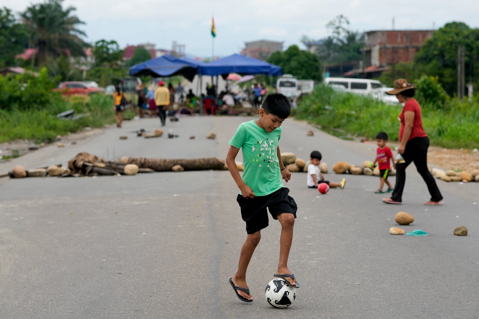 A youth dribbles a soccer ball on a blocked road in Lauca N, Chapare region, Bolivia, Sunday, Nov. 3, 2024, amid an ongoing political conflict between former Bolivia's President Evo Morales and the government of President Luis Arce. (AP Photo/Juan Karita)