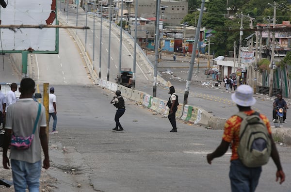 People watch as police officers exchange gunfire with gangs in Port-au-Prince, Haiti, Monday, Nov. 11, 2024. (AP Photo/Odelyn Joseph)