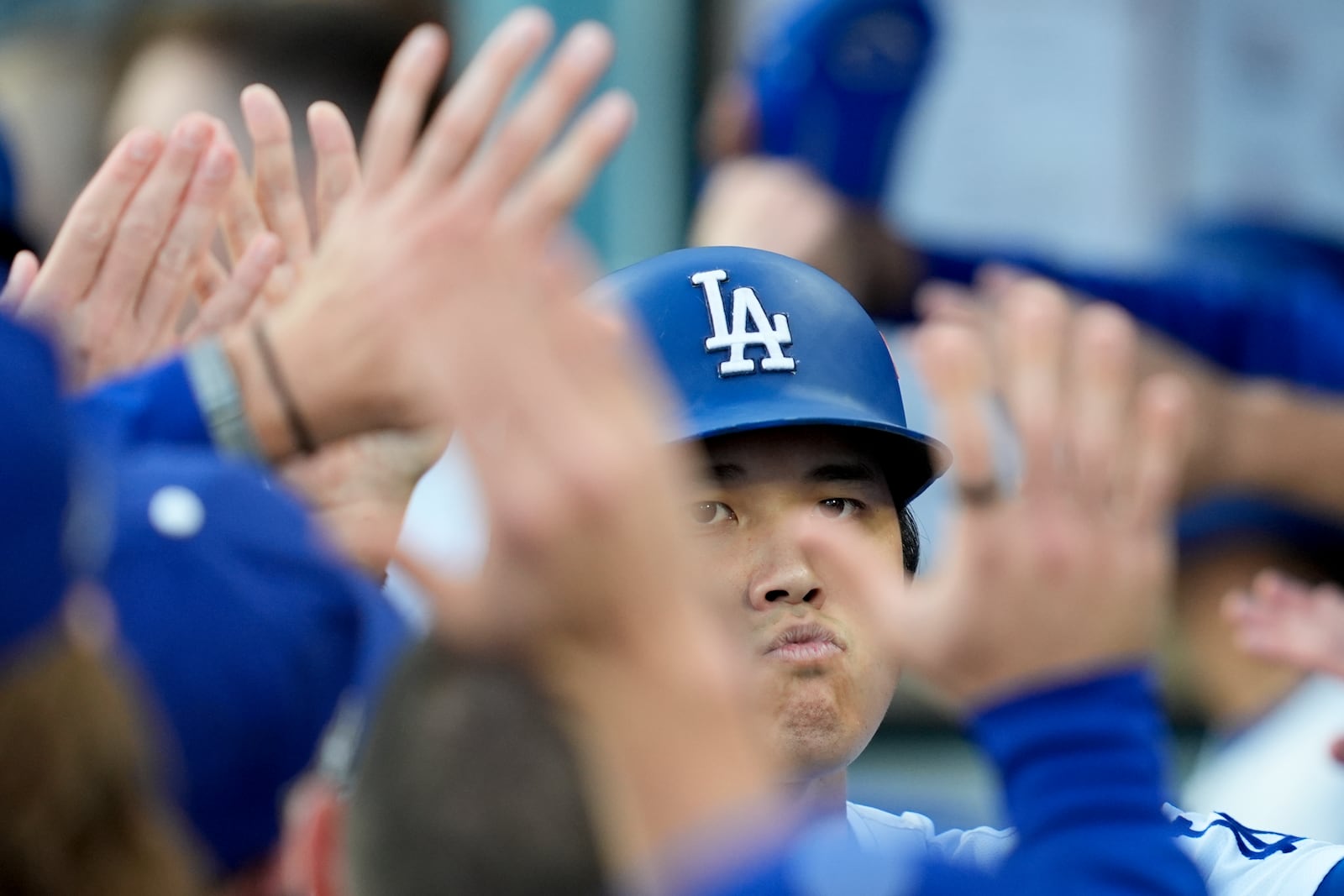 Los Angeles Dodgers' Shohei Ohtani celebrates in the dugout after scoring on a double by Tommy Edman during the first inning in Game 6 of a baseball NL Championship Series against the New York Mets, Sunday, Oct. 20, 2024, in Los Angeles. (AP Photo/Ashley Landis)