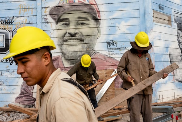 Construction workers stand by a mural of late soccer star Diego Maradona at the stadium of the Argentinos Juniors soccer club in Buenos Aires, Argentina, Tuesday, March 11, 2025. (AP Photo/Rodrigo Abd)