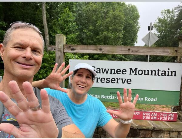 Ken and Karen Cooksey hold up 15 with their hands after walking a 3.8 mile loop at The Sawnee Mountain Preserve in Cumming 15 days in a row. A few times, they walked an additional five miles. (Contributed)