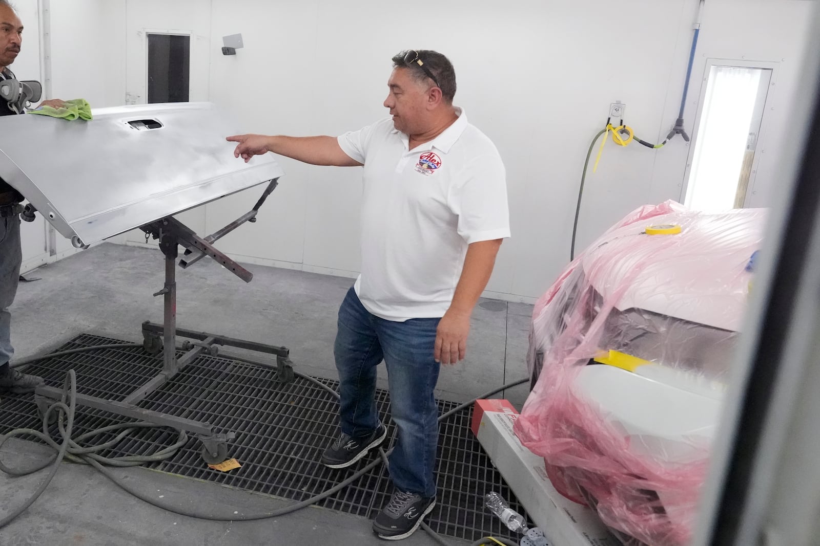 Business owner Alex Salguero checks out a worker's progress at his auto body shop in Lewisville, Texas, Wednesday, Oct. 2, 2024. (AP Photo/LM Otero)