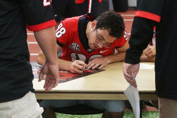 Rodrigo Blankenship signs a poster during UGA Fan Day. Christina Matacotta/Christina.Matacotta@ajc.com