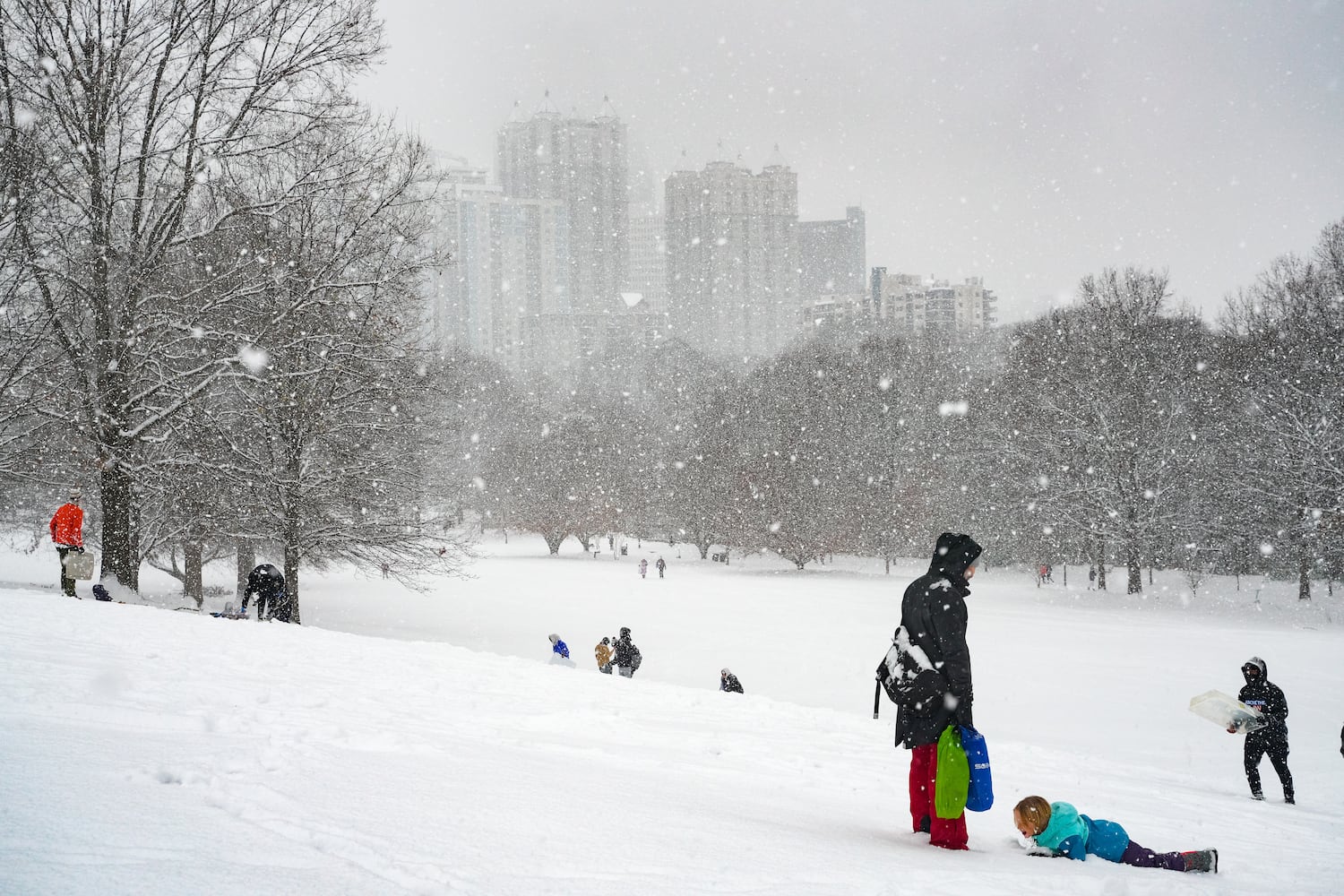 Family's play in the snow inside Piedmont Park. Friday, January 10, 2025 (Ben Hendren for the Atlanta Journal-Constitution)