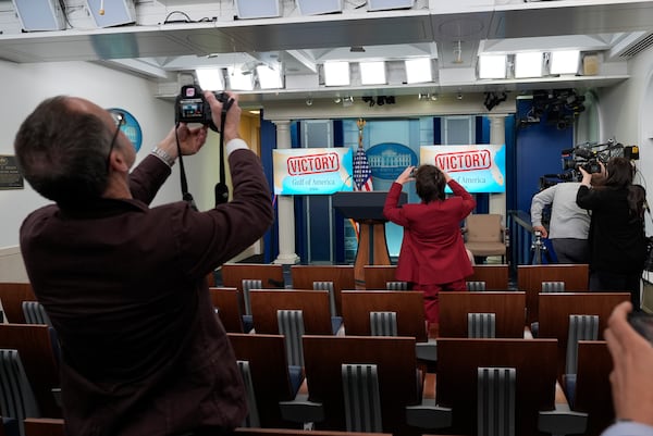 People take photos of monitors behind the podium in the James Brady Press Briefing Room at the White House, Monday, Feb. 24, 2025, in Washington. (AP Photo/Alex Brandon)