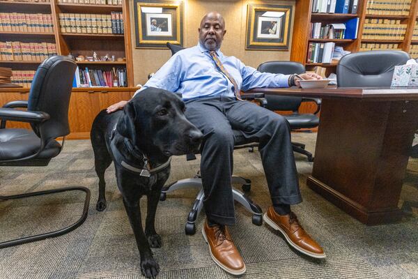 Chief Judge Ural Glanville sits in his Fulton County courtroom office with his service dog, Jack, on Tuesday, Sept. 26, 2023.   (Steve Schaefer/steve.schaefer@ajc.com)