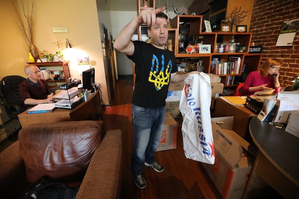 Alex Khodorkovsky holds the sign that bears the name of his travel agency, which used to hang outside his business.  Miguel Martinez for The Atlanta Journal-Constitution 