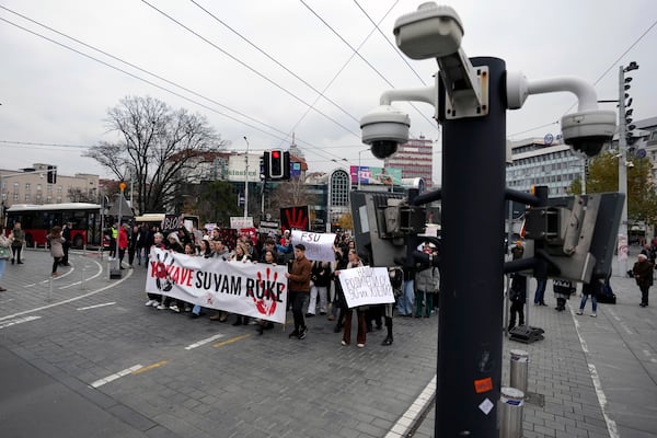 People hold a banner that reads "You have blood on your hands" and stop traffic during a silent protest to commemorate the 15 victims of a railway roof collapse six weeks ago, demand accountability for the tragedy, in Belgrade, Serbia, Friday, Dec. 13, 2024. (AP Photo/Darko Vojinovic)