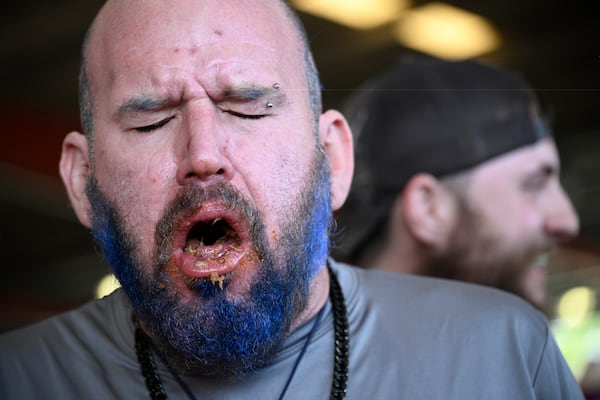 Chris Green, left, of Jacksonville, Fla., reacts while competing in the Eat the (Pork) Butt Challenge during the Florida Man Games, Saturday, March 1, 2025, in Elkton, Fla. (AP Photo/Phelan M. Ebenhack)