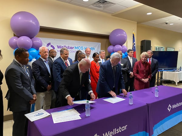 University System of Georgia Chancellor Sonny Perdue, left; Augusta University President Brooks Keel, center; and Wellstar Health System CEO Candice Saunders, right, sign the final papers for Wellstar's takeover of Augusta University Health at Augusta University Medical Center on August 30, 2023.  AU Health will now be called Wellstar MCG Health. (PHOTO by Ariel Hart)