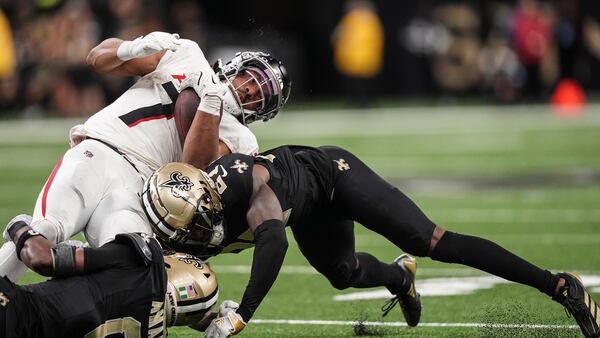 Atlanta Falcons running back Bijan Robinson (7) is hit by New Orleans Saints cornerback Shemar Jean-Charles (27) and safety Ugo Amadi (0) during the second half of an NFL football game, Sunday, Nov. 10, 2024, in New Orleans. (AP Photo/Gerald Herbert)