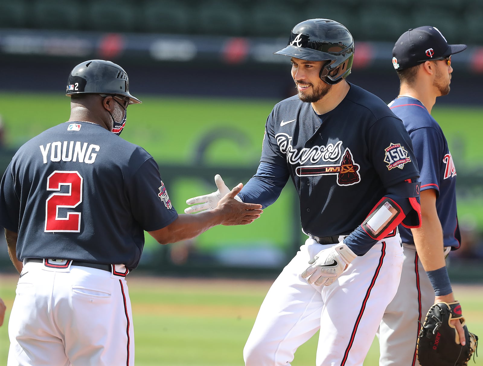 Atlanta Braves catcher Travis d’Arnaud gets five from first base coach Eric Young hitting a single against the Minnesota Twins Friday, March 5, 2021, at CoolToday Park in North Port, Fla. (Curtis Compton / Curtis.Compton@ajc.com)