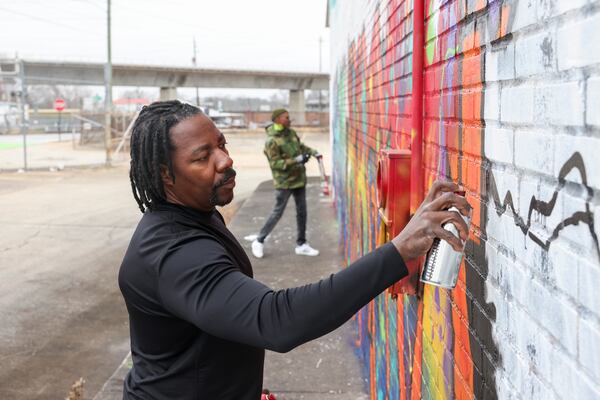 Hackwin "ESKAN" Devoe (left) and Marcus "KRAM" Wallace work on some finishing touches on the wall of a warehouse last month. (Jason Getz / jason.getz@ajc.com)