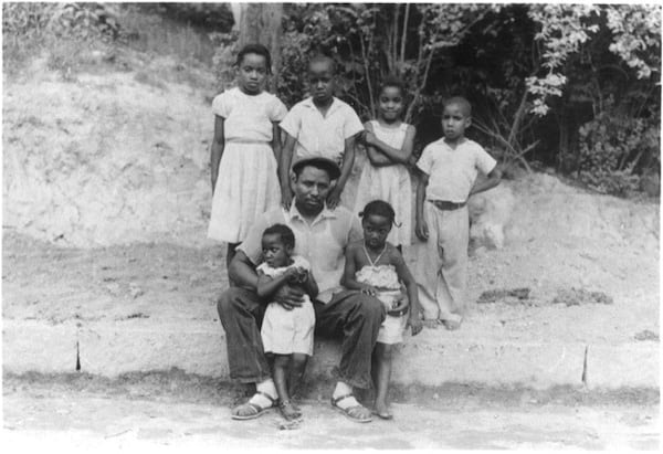 Abe Thomas and six of his seven children outside of their Linnentown home in the 1950s. Hattie Thomas Whitehead, who is spearheading a campaign for reparations and recognition for the descendants of Linnentown, is standing with her arms crossed. Courtesy Hattie Thomas Whitehead.